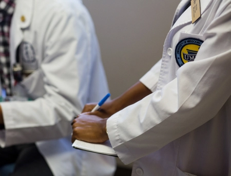 Close up of two people wearing their pharmacy lab coats while talking.