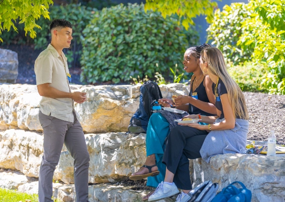 Three pharmacy students talking outside at a student event.