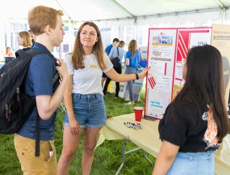 A pharmacy student presents her work at a school sponsored tailgate event.