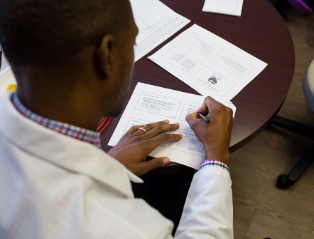 A pharmacy students takes notes at a desk while planning for their future career.