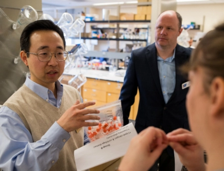 A faculty researcher explains his research to visitors in the lab.