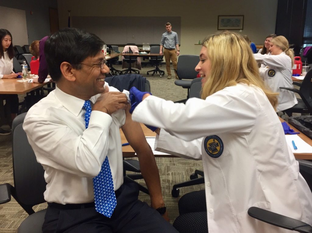 Pharmacy student gives a flu shot to the UMKC Chancellor