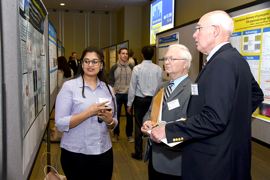 Vrinda Goate presents her poster to two judges at the Research Summit