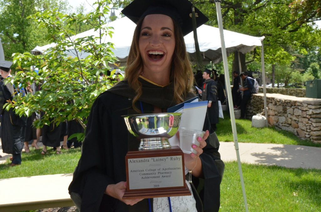 A graduate smiles and poses with award